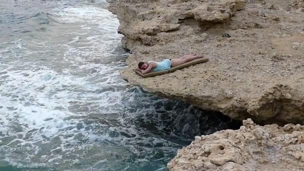 Mädchen schläft in Zeitlupe am steinigen Strand. — Stockvideo