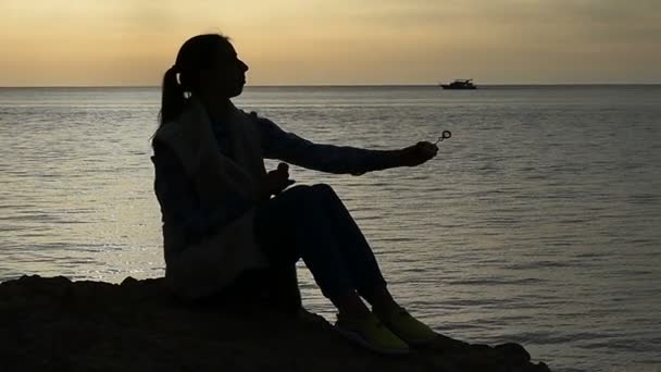 Σιλουέτα του κοριτσιού στο ηλιοβασίλεμα κάνοντας φυσαλίδες με αστείο τρόπο σε αργή κίνηση. — Αρχείο Βίντεο