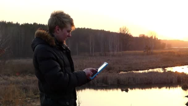 Estudiante rubio trabajando con la tableta al atardecer . — Vídeos de Stock