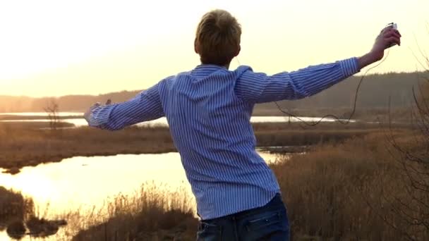 Joven está practicando un poco de danza de ballroon y levantando sus manos con una espléndida puesta de sol en el fondo a principios de primavera en Slo-Mo — Vídeo de stock