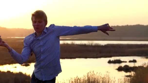Mladý muž je taneční a zvyšování jeho ruce v otočí s nádherný západ slunce v pozadí v brzy na jaře — Stock video