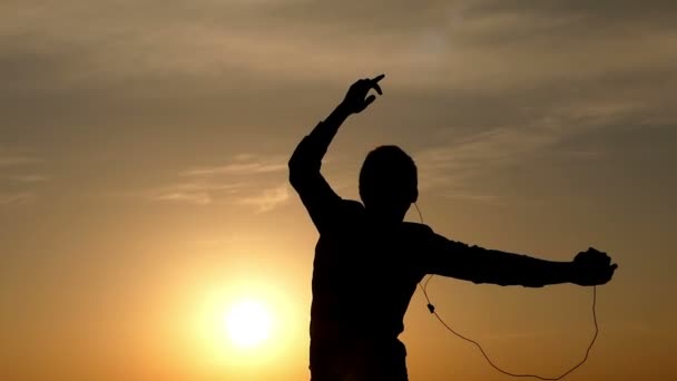 Активный молодой человек танцует и поднимает руки в поворотах с великолепным закатом на заднем плане ранней весной — стоковое видео