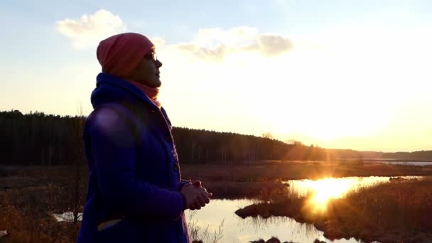 Middelbare leeftijd vrouw in glazen geniet van prachtige zonsondergang in de buurt van Lake. — Stockvideo