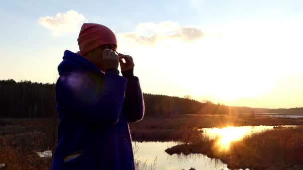 Medelålders kvinna sätter på glasögon och åtnjuter vackra solnedgången. — Stockvideo