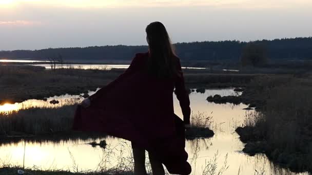 Hermosa modelo en vestido rojo girando y bailando en cámara lenta al atardecer . — Vídeo de stock