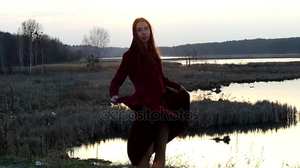 Hermosa modelo en vestido rojo girando y bailando en cámara lenta al atardecer . — Vídeos de Stock