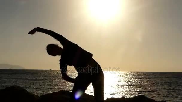 Trener fitness wykonywania Tilt z boku jej ciało o zachodzie słońca na plaży. — Wideo stockowe