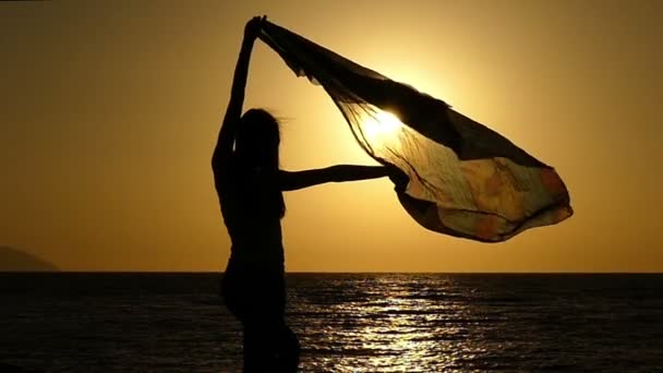 Красива дівчина з парео, стоячи на пляжі на захід сонця у повільному. — стокове відео