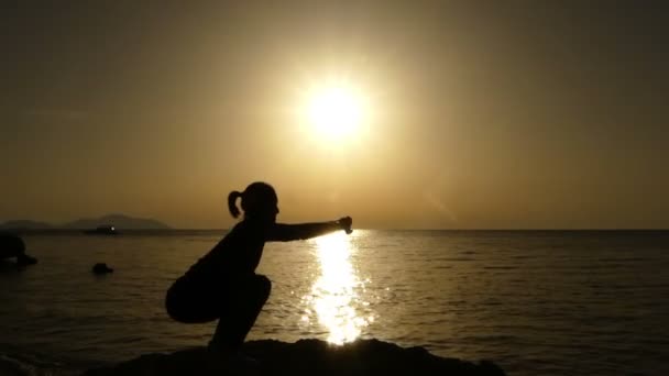 Fitnesstrainerin macht Kniebeugen bei Sonnenuntergang am Strand. — Stockvideo