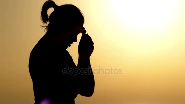Kvinna att hålla ett Christian kors i handen vid solnedgången och be. — Stockvideo