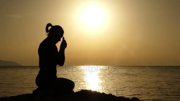 Žena drží Christian kříž v ruce při západu slunce a modlit se. — Stock video