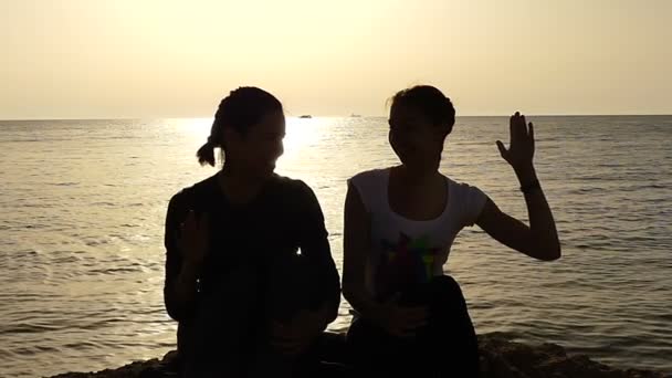 Két fiatal nők a tengerpart csinál magas öt naplementekor. — Stock videók