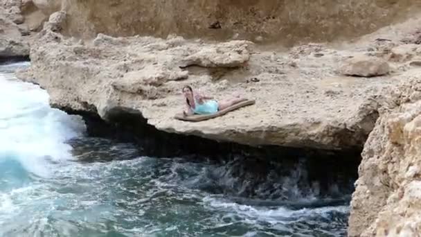 Üzerinde Deniz Cliff altı döşeme ve elini sallayarak kız. — Stok video