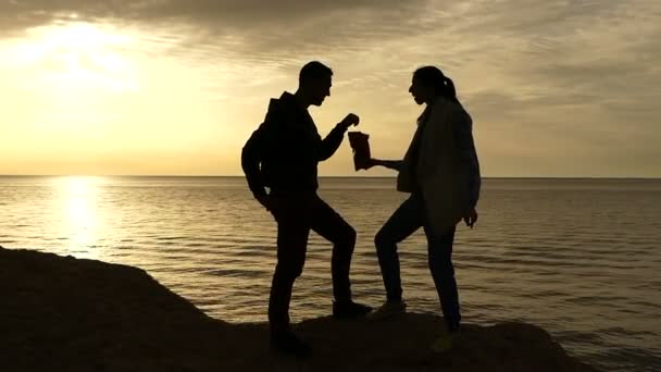 Ζευγάρι τρώγοντας τσιπς στο κίτρινο ηλιοβασίλεμα στην παραλία και χορό. — Αρχείο Βίντεο