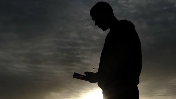 Silhouette nera di un uomo che scrive nel suo taccuino . — Video Stock