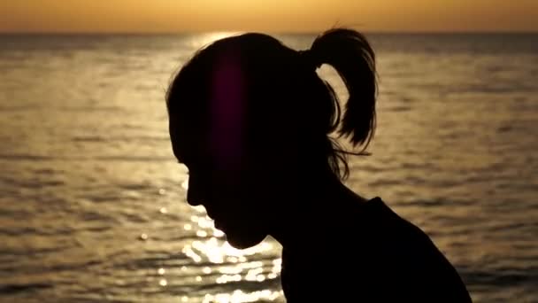 Силует жінка з смартфон з боку на заході сонця на морі. — стокове відео