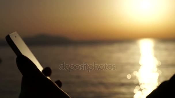 Silhouette de fille qui tient Smartphone au coucher du soleil sur la plage . — Video
