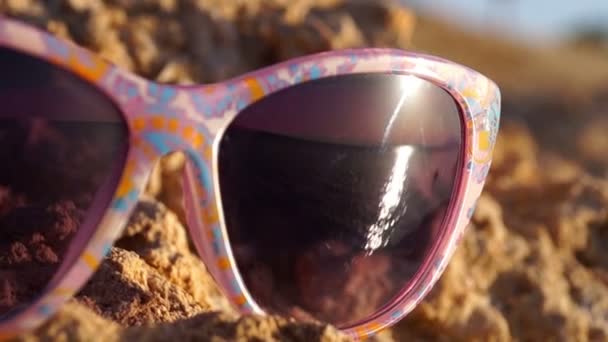 Se concentrer sur les lunettes de soleil avec reflet de beau coucher de soleil sur la mer . — Video