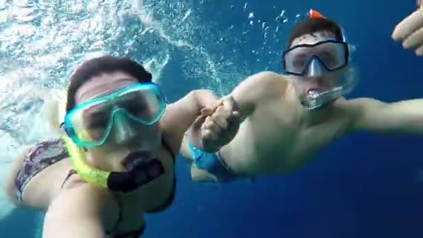 Чоловік і жінка поплавати під водою в Blue Sea утримання для рук і показати великі пальці — стокове відео