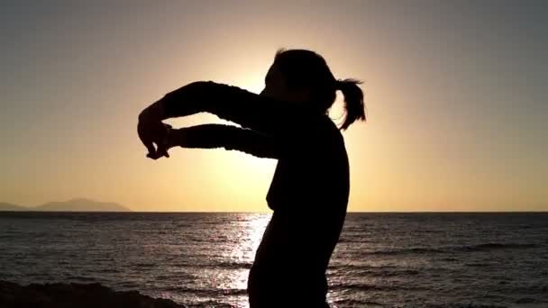 Девочка согревается на закате на пляже . — стоковое видео