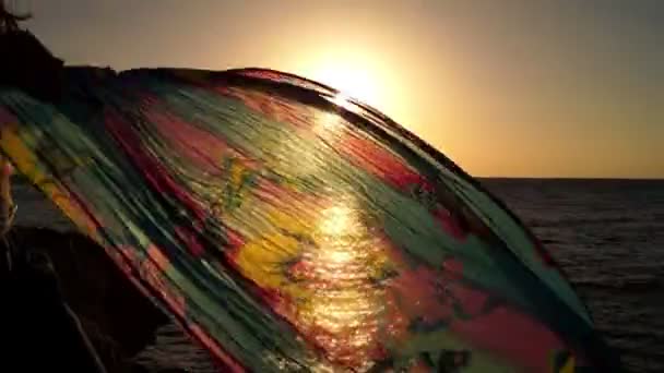 Blåsigt sarong i solnedgången på stranden havet. — Stockvideo