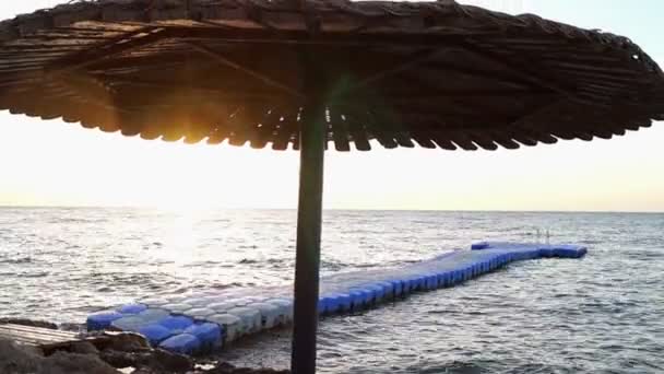 Guarda-chuva na praia do hotel em raios de sol ao pôr do sol . — Vídeo de Stock