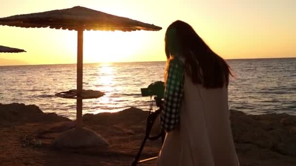 해변에서 선셋에서 일 하는 삼각대와 소녀. — 비디오