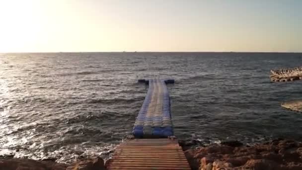 Pont en plastique sur la mer au coucher du soleil ondulant à la surface de l'eau . — Video