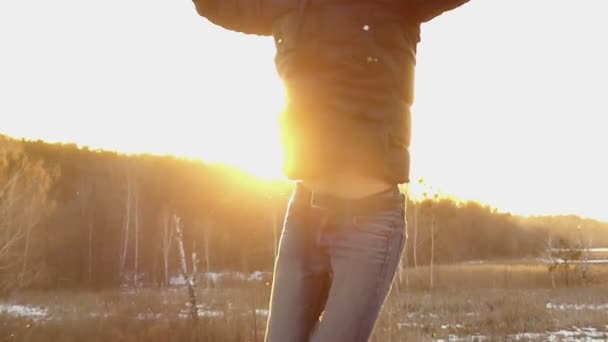 Chico positivo saltando felizmente contra el fondo de un sol brillante en cámara lenta — Vídeo de stock
