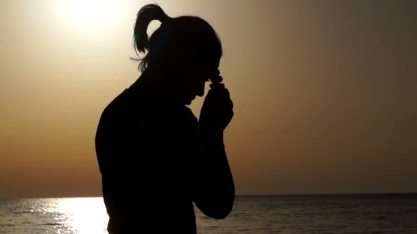 Una ragazza prega su una collina durante il tramonto sullo sfondo del mare — Video Stock
