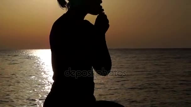 Silhouet van een meisje bidden op de heuvel tijdens zonsondergang — Stockvideo
