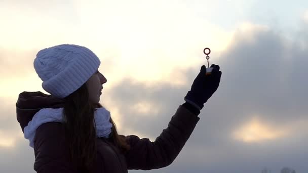 Das Mädchen hält einen Zauberstab für Seifenblasen in der Hand und erzeugt begeistert Blasen unter dem Einfluss des Windes in Zeitlupe — Stockvideo