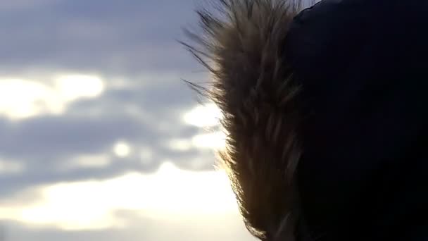 Мех на капюшоне куртки движется в ветре на фоне голубого неба в медленном движении — стоковое видео