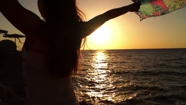 Fille mince tenant Pareo dans les mains sur le temps venteux pendant le coucher du soleil . — Video