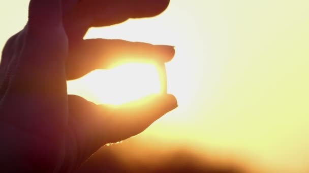 Weibliche Hand hält eine Pille während des Sonnenuntergangs, Nahaufnahme, das Sonnenlicht dringt in die Hand ein — Stockvideo