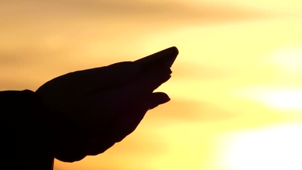 Händer driva något på pekskärmen av tabletten, kan du se deras silhuett mot den vackra Twilight himlen — Stockvideo