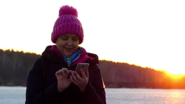 En vacker kvinna är att trycka på något på skärmen Touch av telefonen, ler och visar en gest "ok". — Stockvideo