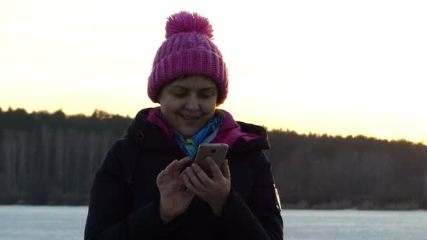 Piękna kobieta naciska coś na ekranie dotykowym telefonu i uśmiechając się. — Wideo stockowe