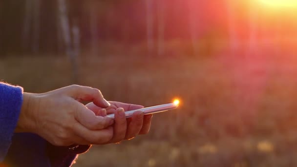 Erkek Closeup Flip bilgi güzel bir arka plan bulanık bir Smartphone Dokunmatik ekran üzerinde eller, güneş ışınları arka ışık oluştur — Stok video