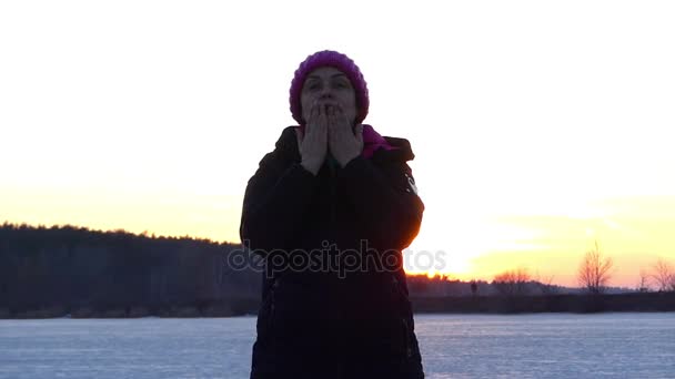 Μια ενήλικη γυναίκα χαρωπά στέλνει ΙΤΕ ένα φιλί αέρα στο φόντο της ένα χειμερινό τοπίο στο ηλιοβασίλεμα — Αρχείο Βίντεο