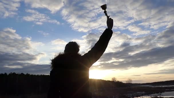 En pojke står med hans tillbaka till oss mot bakgrund av pittoreska natur och tryggt höjer upp hans Trophy i Slow Motion — Stockvideo