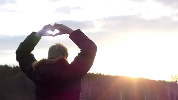 Personen med ryggen mot kameran håller händerna i form av hjärtat, sedan sänker gradvis dem i Slow Motion — Stockvideo