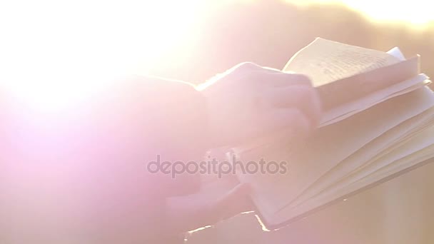 En Personleafing genom de sidor av en bok utomhus nära i solljus, i Slow Motion — Stockvideo