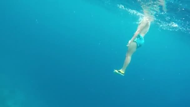 Hombre en pantalones cortos azules se sumerge en el mar  . — Vídeos de Stock