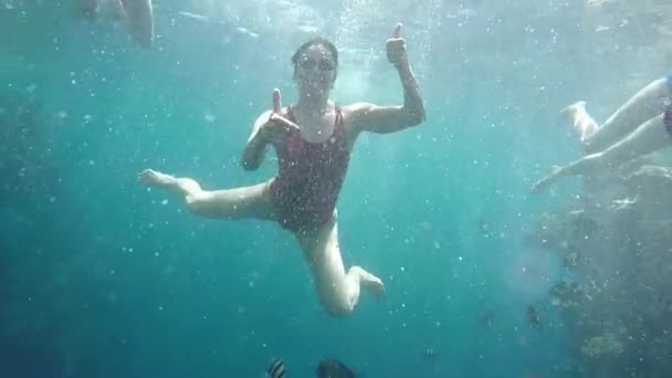 Улыбающаяся молодая женщина, снятая под водой в водах Красного моря в солнечный день — стоковое видео