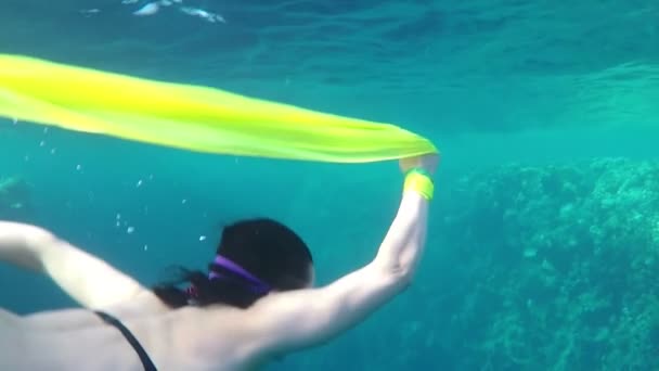 Jonge vrouw zwemt en houdt een geel doek in Hand in de heldere wateren in Slo-Mo — Stockvideo