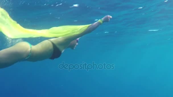 Молодая женщина во Флипперсах плавает с белой тканью в голубых водах моря в Сло Мо — стоковое видео