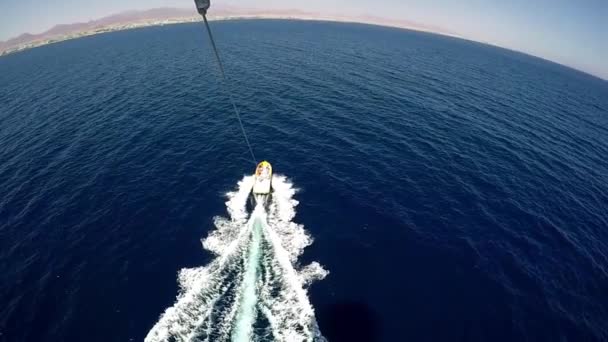 Мощный катер с туристами тянет парашют на веревке в солнечный день — стоковое видео