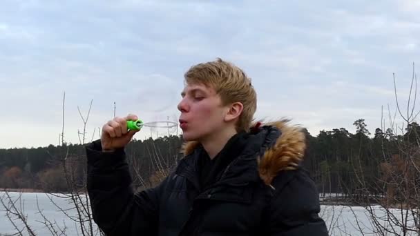 En ström av Rainbow såpbubblor är lägrade av en Man på en gräsmatta i Slo-Mo — Stockvideo