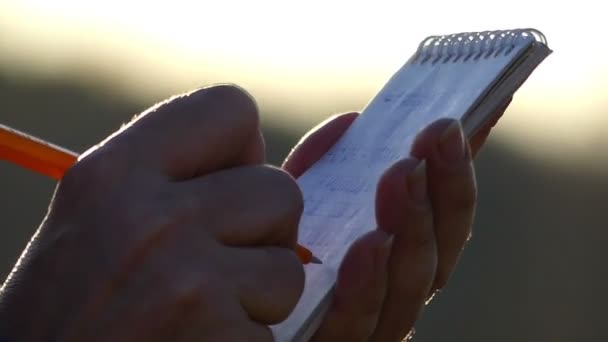 Руки дорослої жінки Пишіть в блокноті крупним планом на розмитому тлі — стокове відео